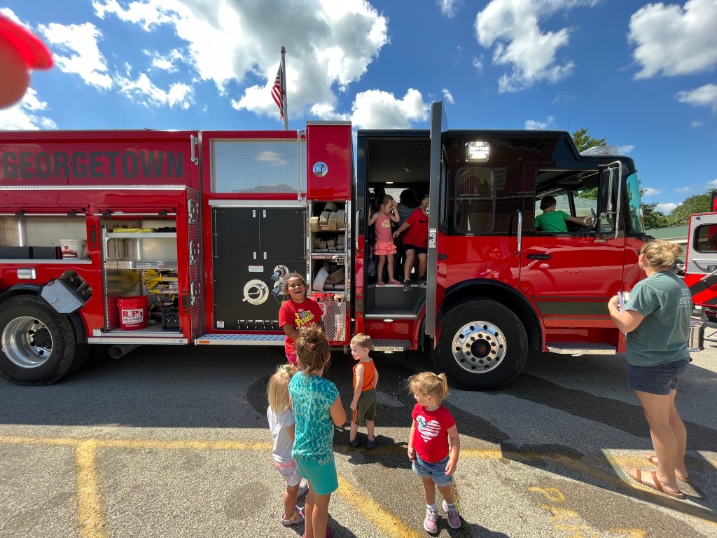 Kids standing in front of a fire truck.